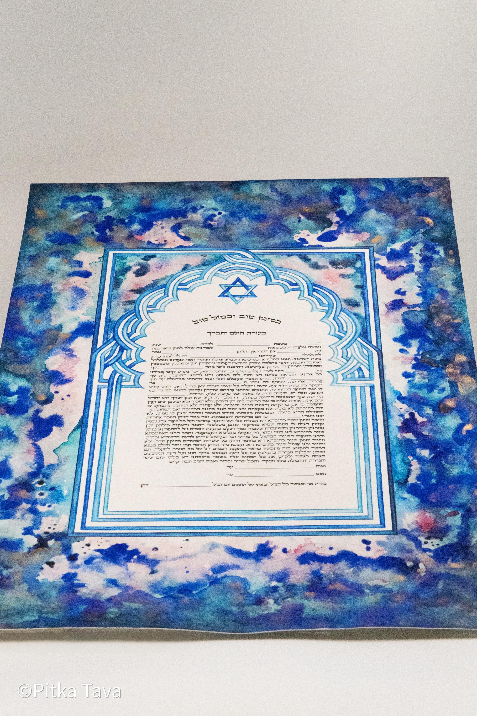 Jewish ketubah handmade for chuppah jewish wedding maroccan style with blue and white magen David colors like the Talith. Watercolor painting handmade ketubbah with sunset colors in maroccan style, unique one of a kind wedding ketubbah piece of jewish art made in israel by designer ketubbah. Illustrated blue, pink and white ketubah with sunset colors and blue and white colors around the text to remember blue colors of Am Israel.